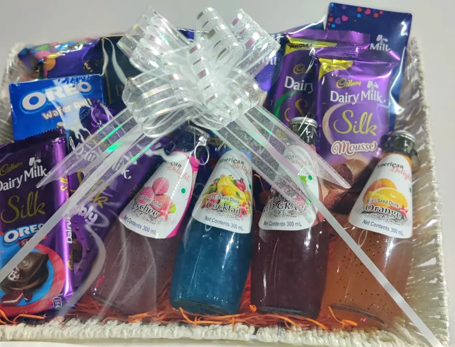 A tray hamper of Cadbury chocolate bars and bottled basil-seed drinks, tied with a silver ribbon