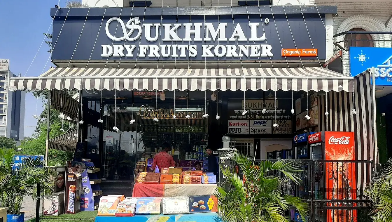 The shopfront by day: white lettering on a navy board, a charcoal and cream striped awning, and boxed sweets laid out on tables at the front